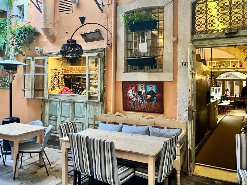 Venkovní restaurace Avli Lounge Apartments v historickém Rethymnu s romantickým posezením mezi kamennými zdmi