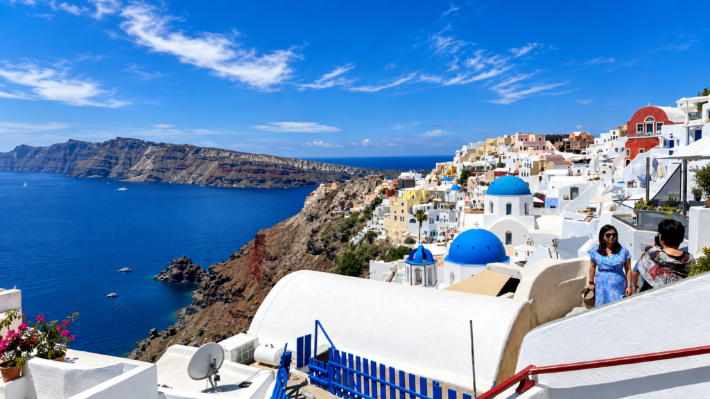 Pohled na Oiu na Santorini s bílými domy, modrými kopulemi a kalderou